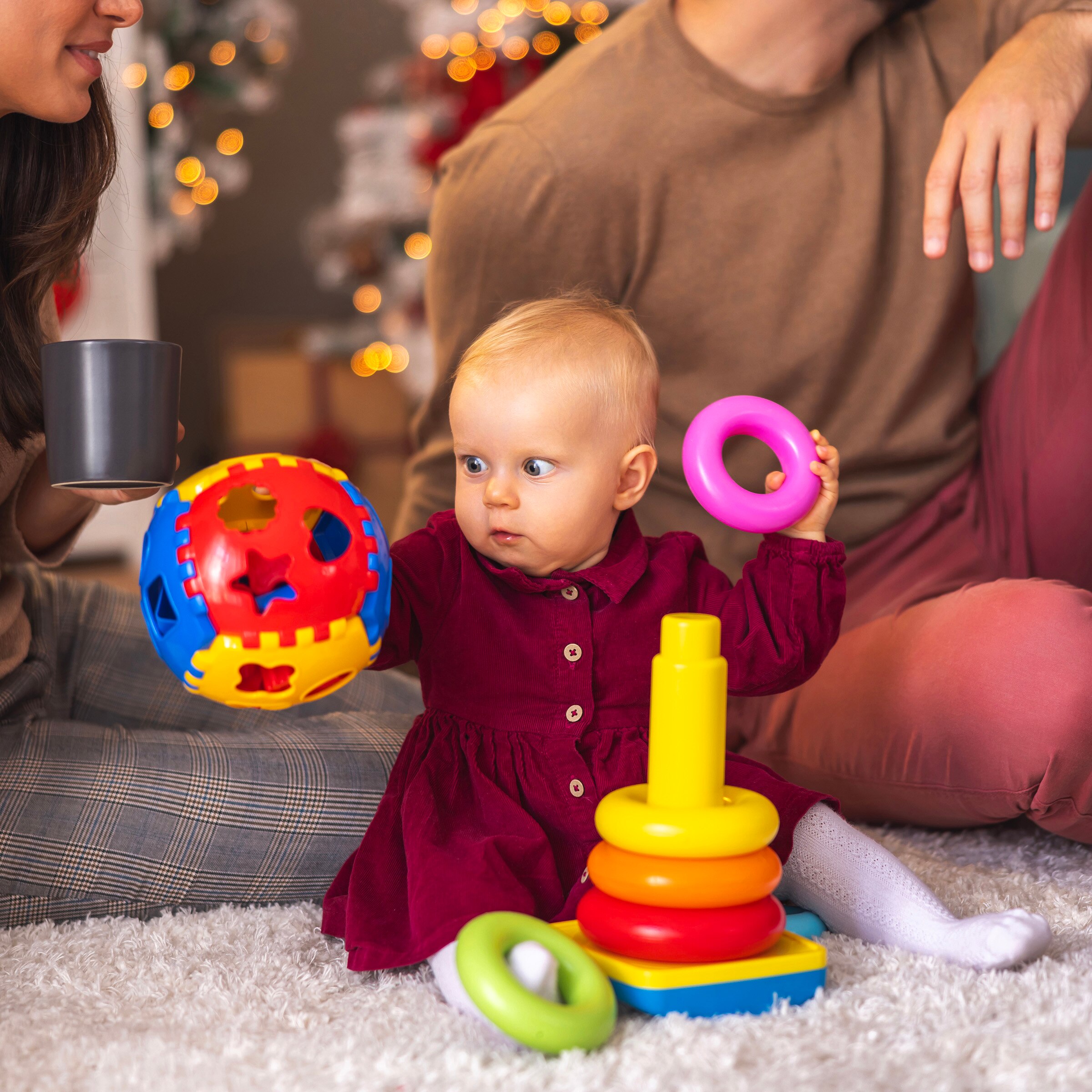Baby playing with holiday gifts with family in the background