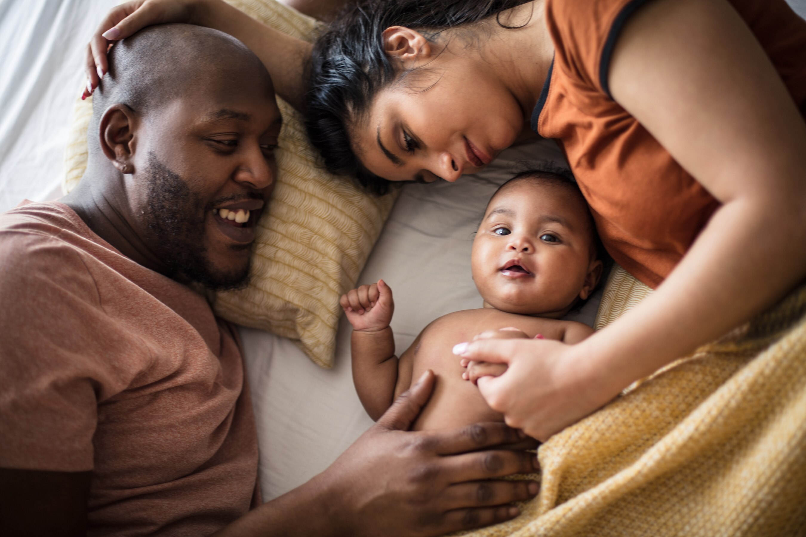 Couple snuggling with baby in bed