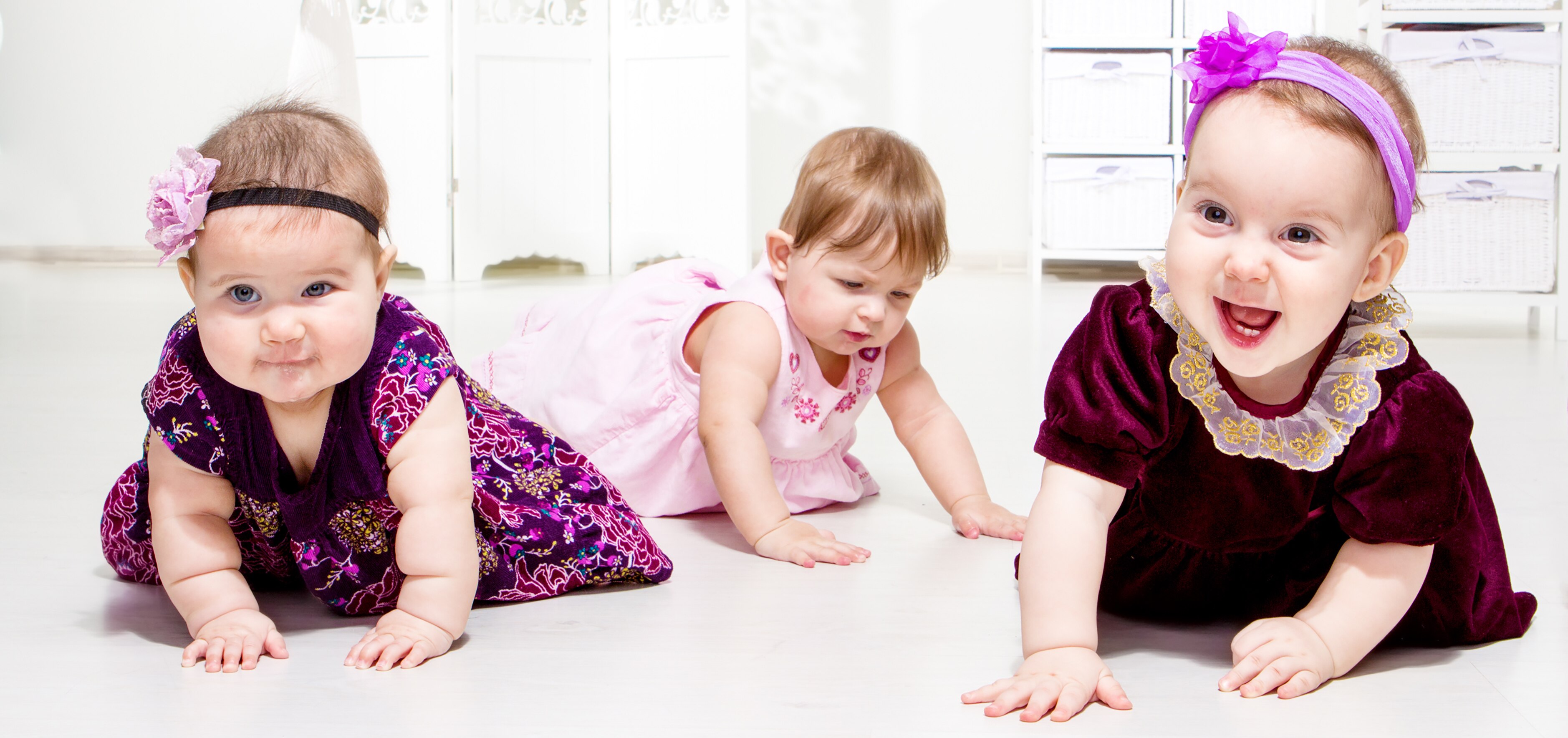 Crawling baby girls wearing holiday dresses