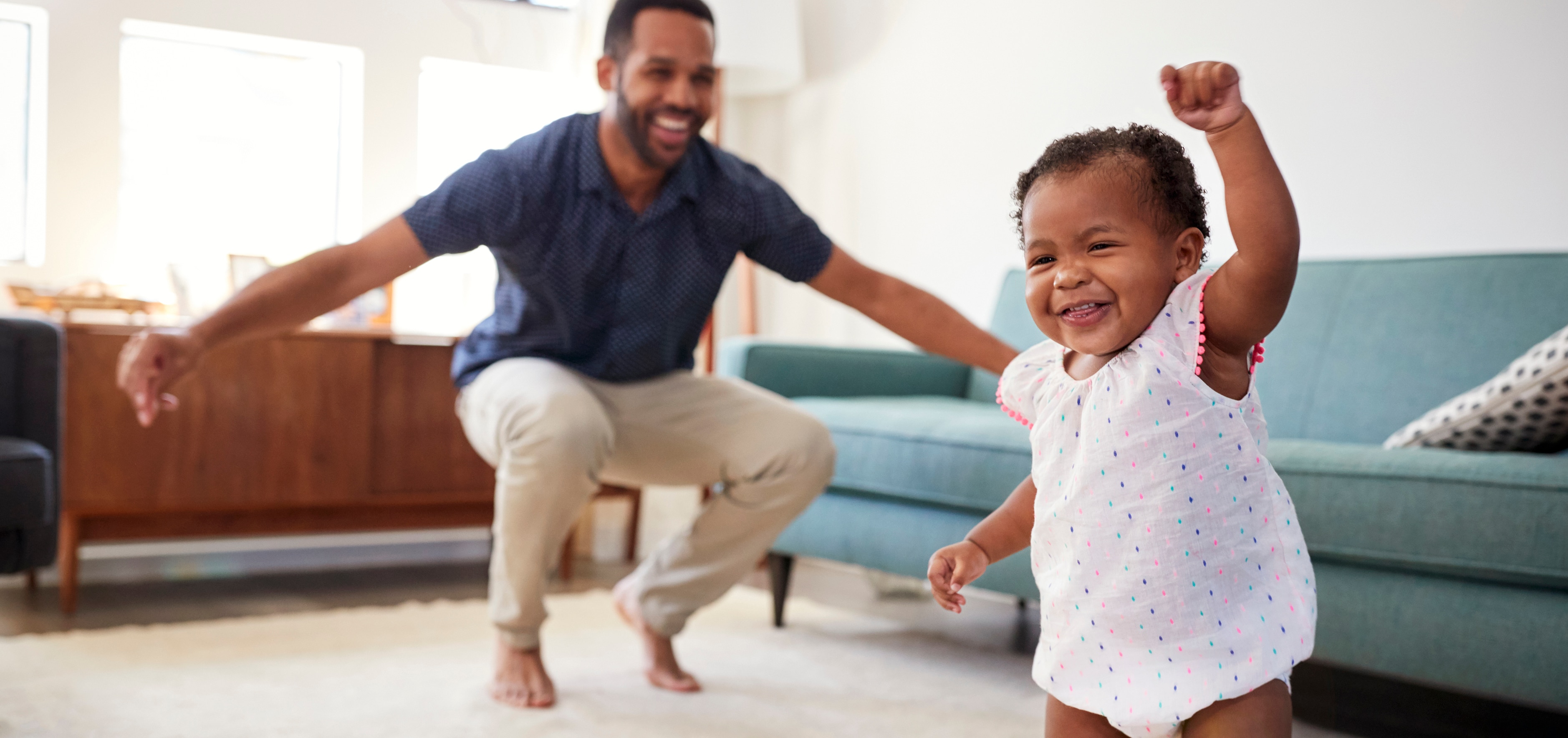 Father and baby daughter dancing together in the living room