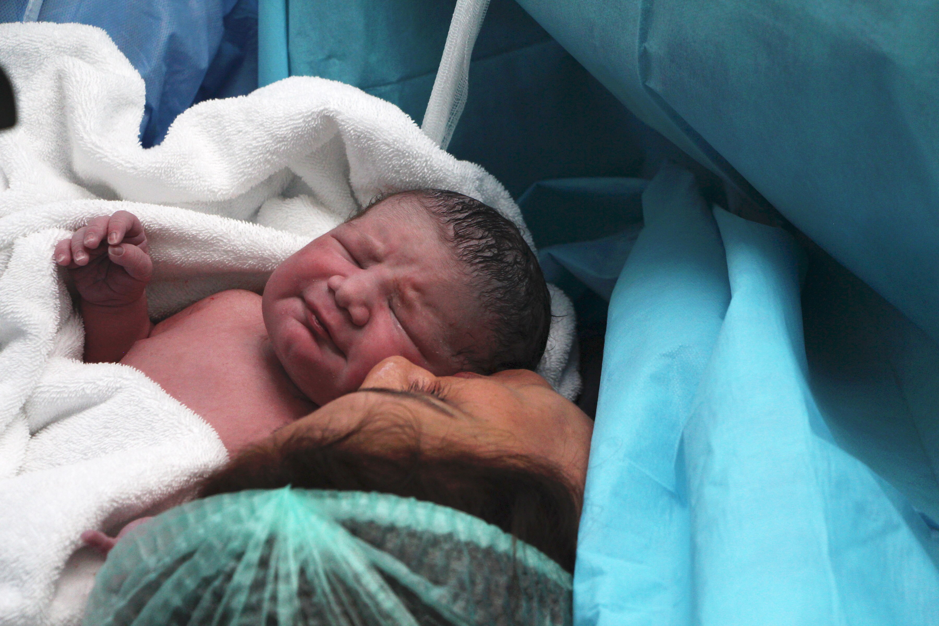 Mom admiring just delivered newborn in hospital