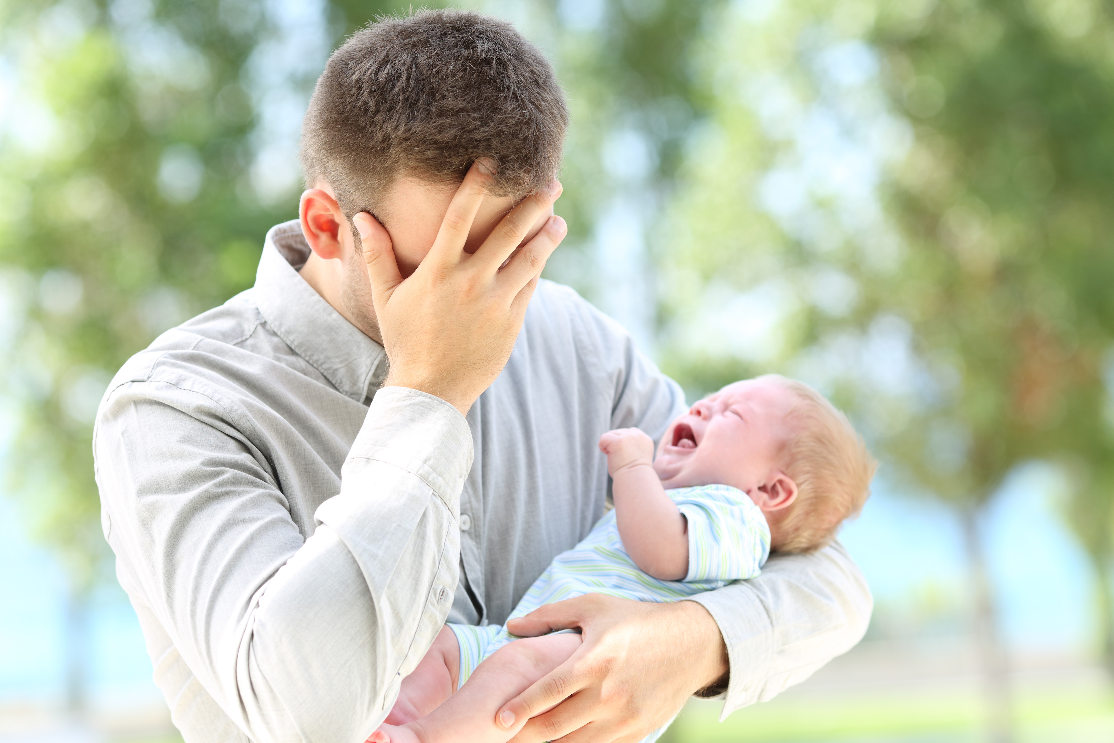 Overwhelmed dad holding crying baby