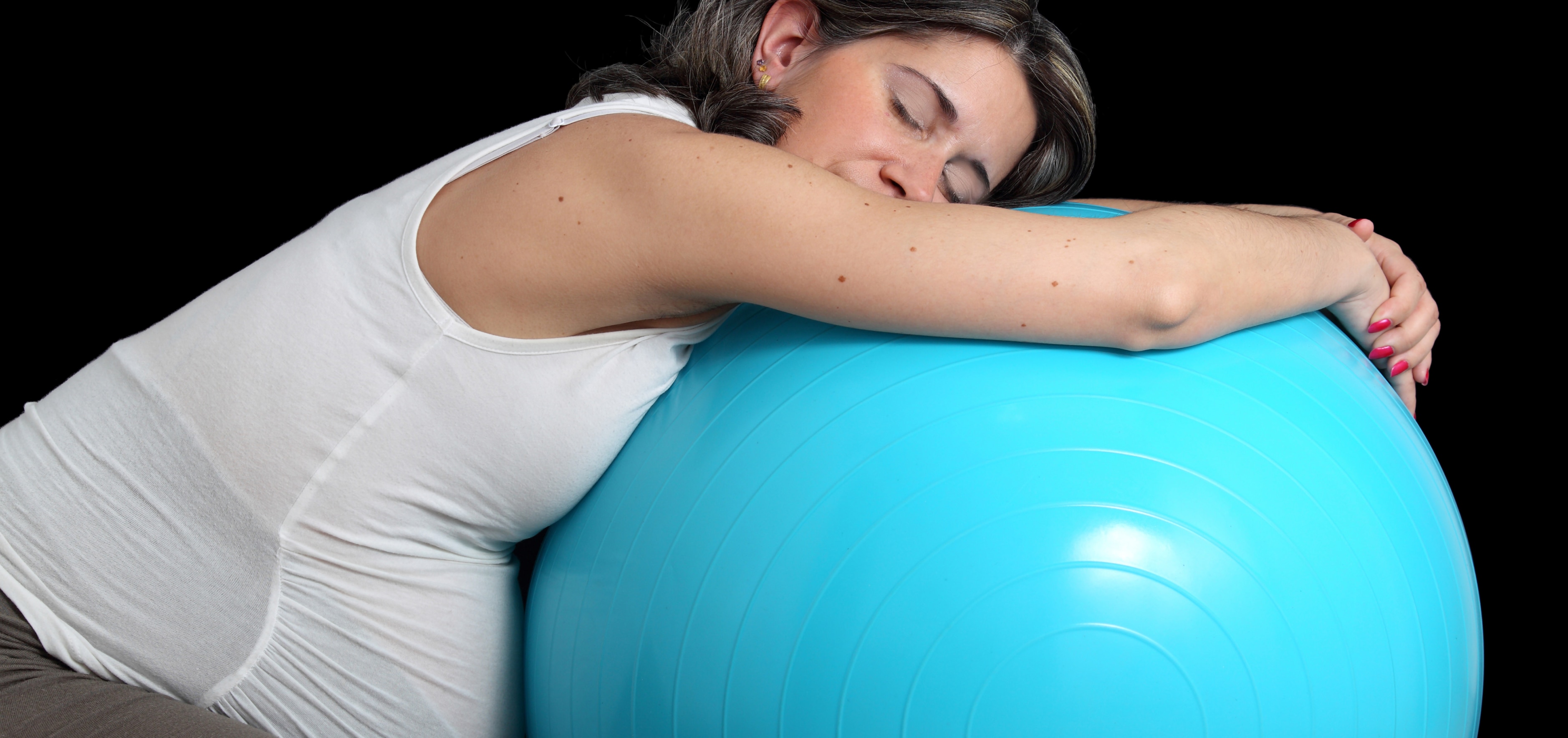 Pregnant woman kneeling over a birth ball
