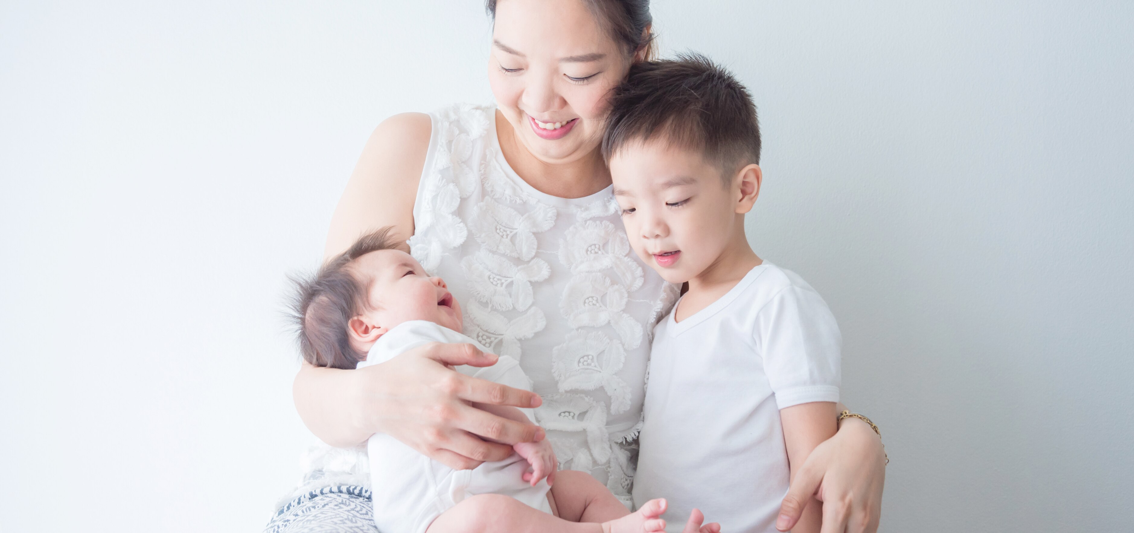 smiling mother cuddling her baby and toddler